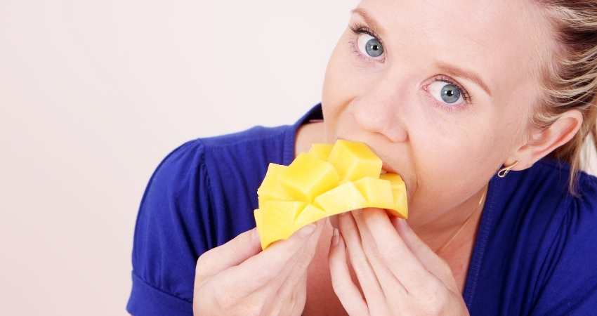 A woman tasting a mango.