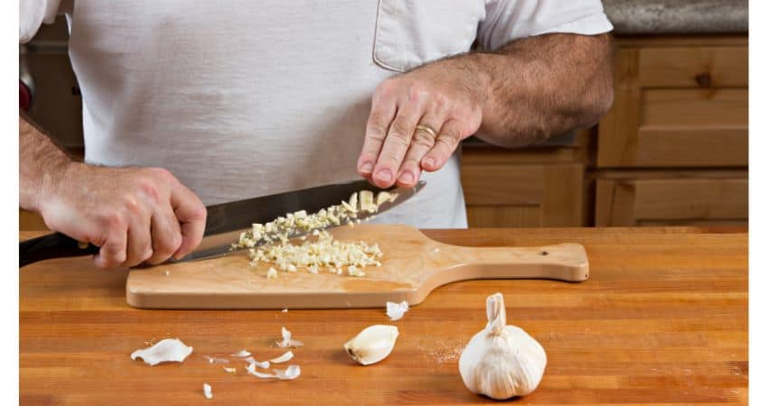 Mincing garlic with a knife.