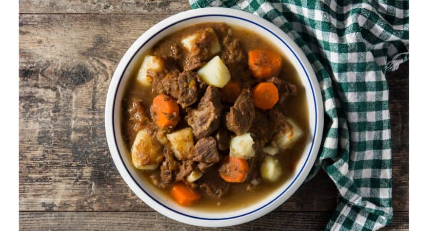 Beef stew in a bowl with carrots and potatoes.