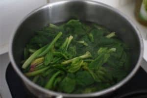 Blanching spinach in a pot.